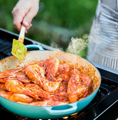 person cooking prawns with dusos traditional tomato sauce on an outdoor bbq