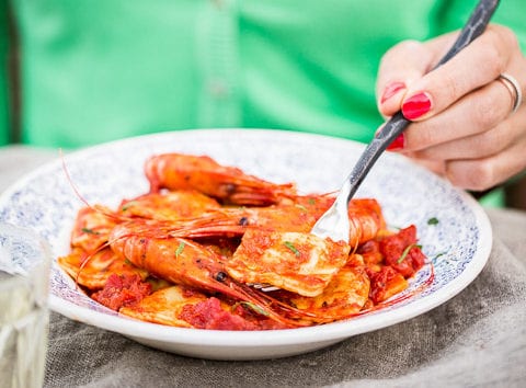 woman enjoying cooked cheese ravioli with prawns and tomato sauce